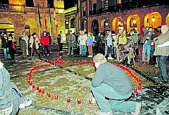 Javier, agachado, de espaldas, coloca una vela del lazo del sida que ayer se realiz en la plaza Mayor gijonesa.